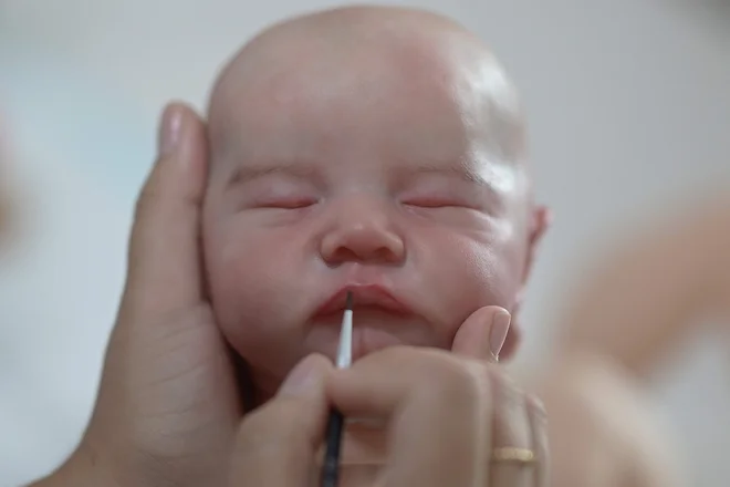 Ana Paula Guimaraes izdeluje superrealistično lutko v svojem studiu v brazilskem mestu Contagem. Superrealistične lutke, imenovane »ponovno rojeni otroci« (Reborn Babies), vsebujejo podrobnosti, kot so nohti, trepalnice, žile, gube in lise na telesu, zaradi katerih so punčke videti kot pravi dojenčki. Punčke stanejo 1300 ameriških dolarjev, v povprečju pa jo izdeluje sedem dni. FOTO: Douglas Magno/AFP

