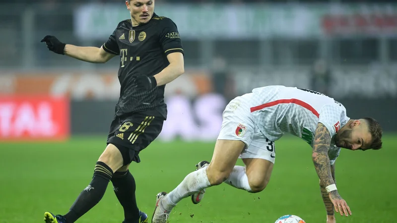 Fotografija: Marcel Sabitzer (levo) in Niklas Dorsch sta se spopadla za žogo na bavarskem obračunu v Augsburgu. FOTO: Christof Stache/AFP