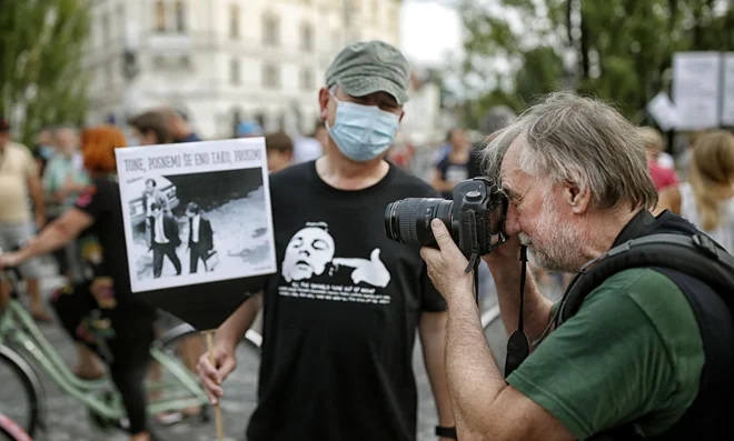 Tone Stojko fotografira protestnika, ki nosi njegovo fotografijo iz leta 1988. FOTO: Blaž Samec/Delo
