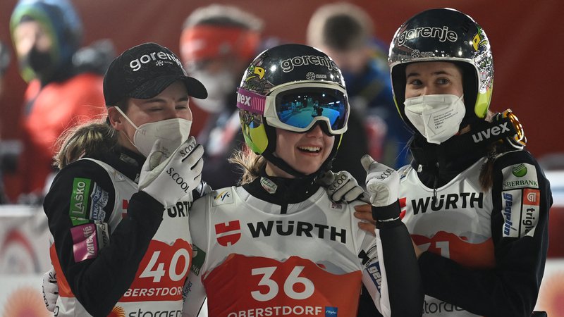 Fotografija: Nika Križnar (levo) in Urša Bogataj (desno) sta se tudi včeraj v Nižnem Tagilu – tako kot konec letošnjega februarja na svetovnem prvenstvu v Oberstdorfu – veselili uspeha Eme Klinec (na sredini). FOTO: Christof Stache/AFP
