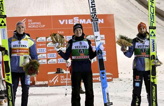 Nasmejanemu zmagovalcu Anžetu Lanišku (na sredini) sta družbo na odru za najboljše delala Nemca Karl Geiger (levo) in Markus Eisenbichler (desno). FOTO: Heikki Saukkomaa/AFP
