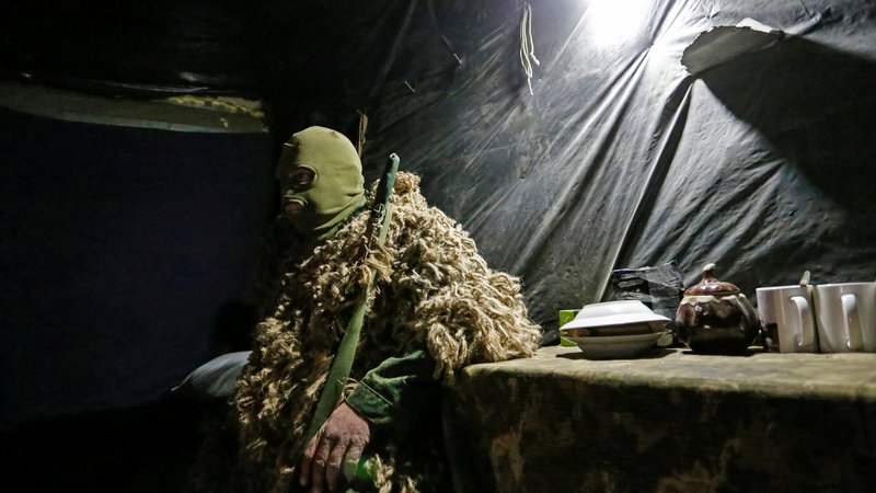 Fotografija: Ostrostrelec iz uporniške Doneške ljudske republike nadzira razmejitveno črto, ki utegne postati zelo vroča fronta nove hladne vojne. FOTO: Aleksander Ermočenko/Reuters
