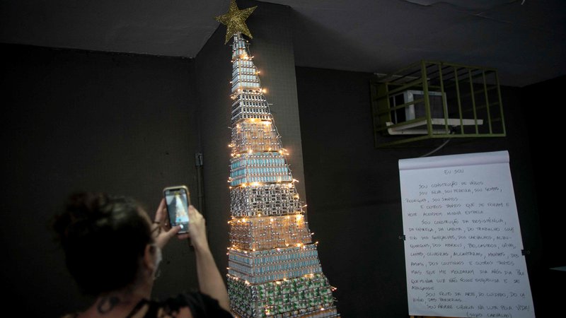 Fotografija: A woman takes photos of a christmas tree made with COVID-19 and Flu vaccine vials at the Public Health Basic Unit "Ernani Agricola", in the Lapa neighborhood in Rio de Janeiro, Brazil, on December 9, 2021. - Health professionals of the unit made the Christmas tree as a way to raise awareness on vaccination locally in its neighborhood but a photo of the tree went viral on Twitter and called attention nationwide. (Photo by MAURO PIMENTEL/AFP)
