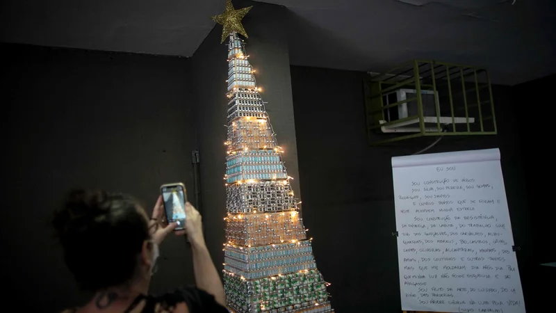 Fotografija: A woman takes photos of a christmas tree made with COVID-19 and Flu vaccine vials at the Public Health Basic Unit "Ernani Agricola", in the Lapa neighborhood in Rio de Janeiro, Brazil, on December 9, 2021. - Health professionals of the unit made the Christmas tree as a way to raise awareness on vaccination locally in its neighborhood but a photo of the tree went viral on Twitter and called attention nationwide. (Photo by MAURO PIMENTEL/AFP)