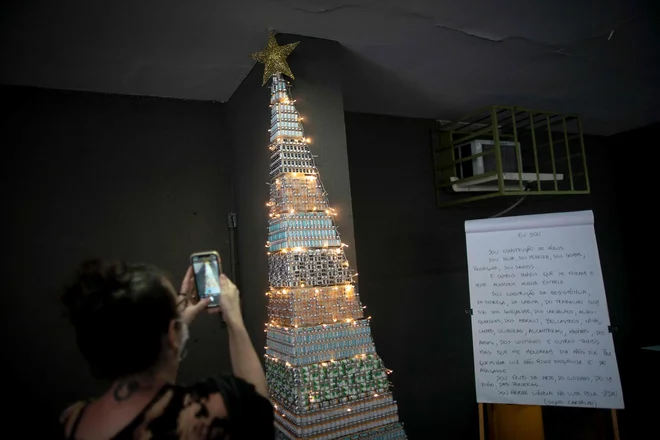 A woman takes photos of a christmas tree made with COVID-19 and Flu vaccine vials at the Public Health Basic Unit &quot;Ernani Agricola&quot;, in the Lapa neighborhood in Rio de Janeiro, Brazil, on December 9, 2021. - Health professionals of the unit made the Christmas tree as a way to raise awareness on vaccination locally in its neighborhood but a photo of the tree went viral on Twitter and called attention nationwide. (Photo by MAURO PIMENTEL/AFP)
