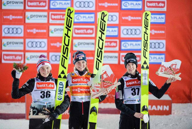 Urša Bogataj (desno) se je veselila že svojih tretjih stopničk v olimpijski zimi. Nasmejani sta bili tudi avstrijska zmagovalka Marita Kramer (na sredini) in drugouvrščena Norvežanka Silje Opseth (levo). FOTO: Jens Schlueter/AFP
