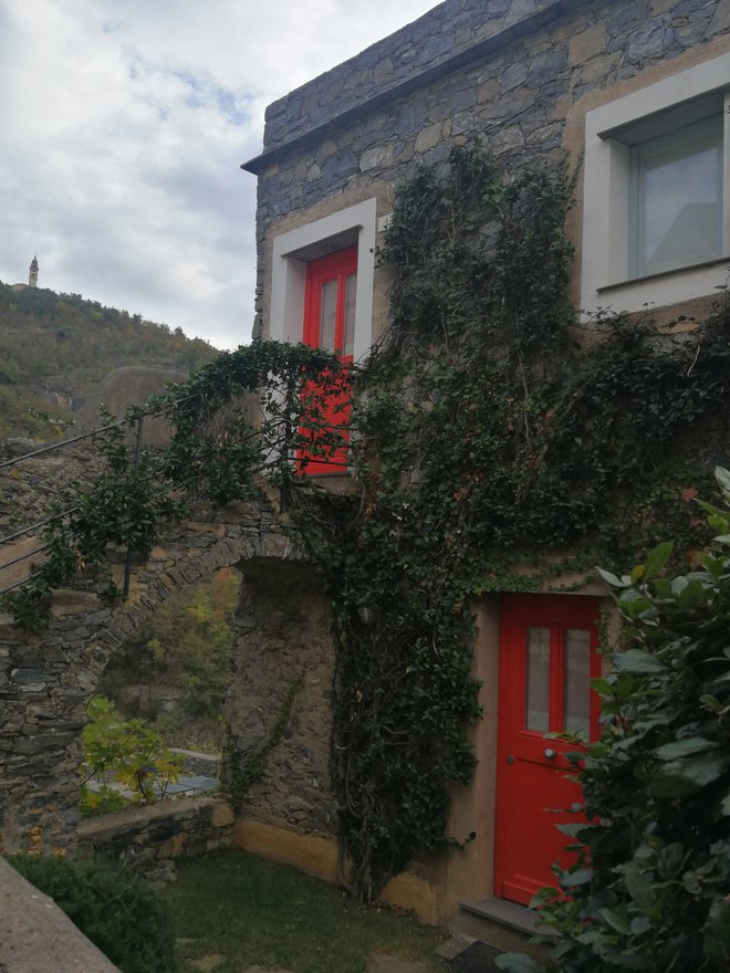 Okna v vasi so pravljično obrobljena z belo, vrata pa obarvana v rdečo ali modro. Foto Maja Grgič
