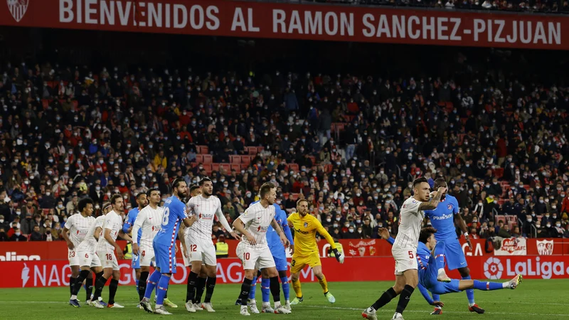 Fotografija: Jan Oblak, v rumenem dresu, v gneči v Sevilli ni zatrl domačih nogometašev, ti so v belih dresih. FOTO: Marcelo Del Pozo/Reuters
