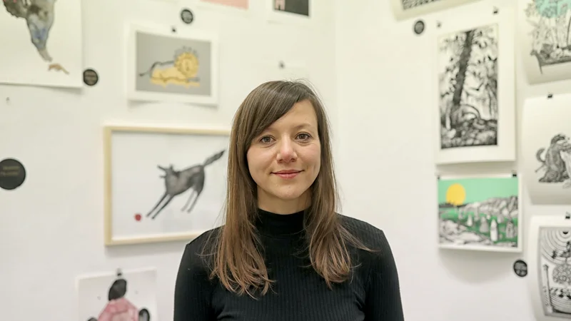 Fotografija: Maša P. Žmitek ob lastnem ustvarjalnem delu vodi Galerijo Vodnikove domačije Šiška, kjer vsako leto zaživi Decembrski sejem ilustracije. FOTO: Blaž Samec