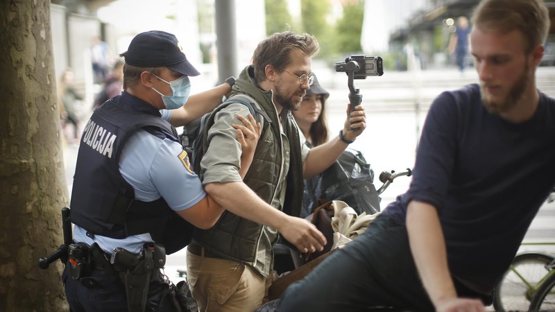 Fotografija: Jaša Jenull ob prijetju policistov pred sedežem SMC. Razlog je bilo pisanje s kredo po pločniku. FOTO: Jure Eržen/Delo
