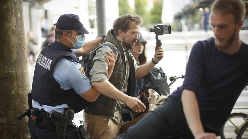 Fotografija: Jaša Jenull ob prijetju policistov pred sedežem SMC. Razlog je bilo pisanje s kredo po pločniku. FOTO: Jure Eržen/Delo