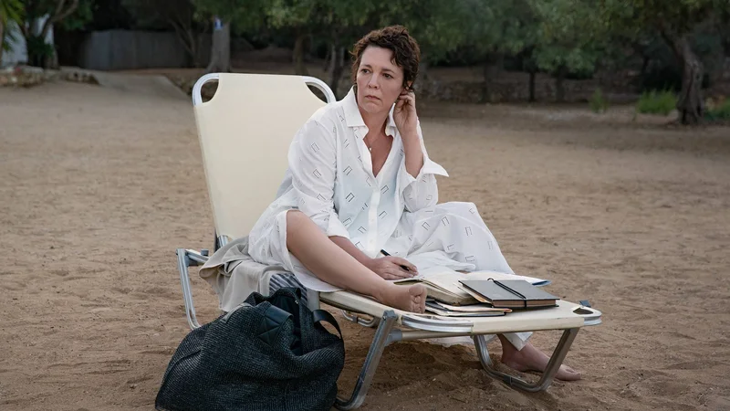 Fotografija: Univerzitetna profesorica Leda Caruso (Olivia Colman) prebira Danteja, je sladoled, plava in poskuša spati, čeprav ji sobo razsvetljuje žarek bližnjega svetilnika. FOTO: Yannis Drakoulidis/Netflix