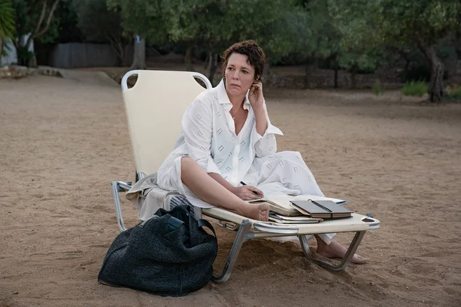 Univerzitetna profesorica Leda Caruso (Olivia Colman) prebira Danteja, je sladoled, plava in poskuša spati, čeprav ji sobo razsvetljuje žarek bližnjega svetilnika. FOTO:&nbsp;Yannis Drakoulidis/Netflix
