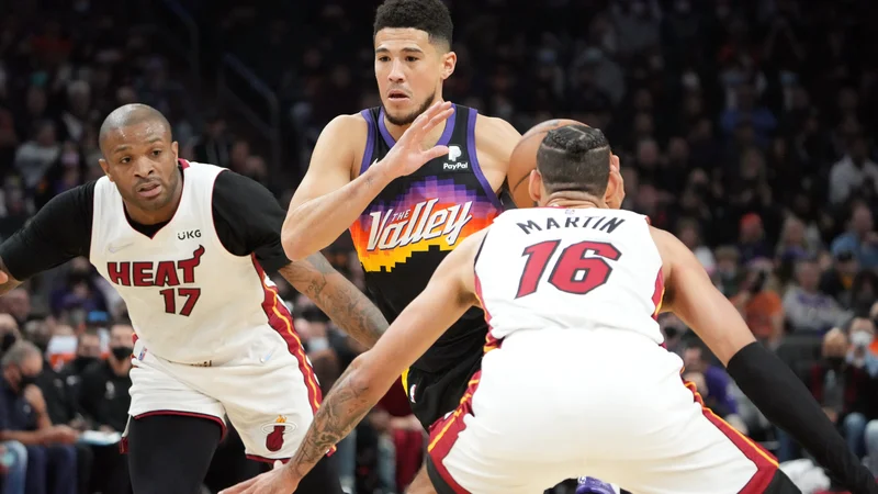 Devin Booker prodira ob P.J. Tuckerju in Calebu Martinu v domači dvorani Footprint Center. FOTO: Joe Camporeale/USA TODAY Sports
