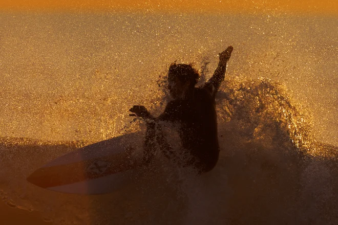 Surfer jaha val, ko sonce zahaja, na plaži Seaside Beach v kalifornijskem mestu Encinitas. Foto: Mike Blake/Reuters

&nbsp;
