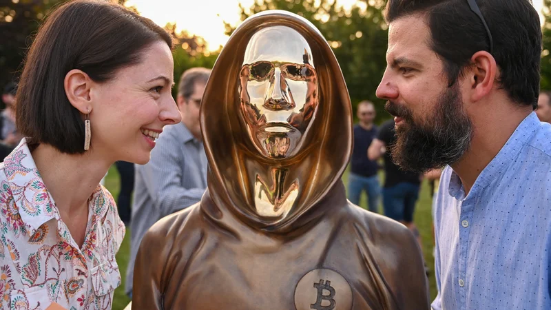 Fotografija: Kiparja Reka Gergely in Tamas Gilly ob kipu izumitelja bitcoina Satoshija Nakamote. FOTO: Attila KisbenedekyAFP