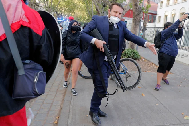Preiskovalni policist se sooča s sorodniki pripornikov med civilno vstajo proti socialni neenakosti v Santiagu, ki se je začela že oktobra 2019. Protestniki so se odpravili proti vladi novoizvoljenega čilskega predsednika Gabriela Borica. Foto: Javier Torres/Afp
