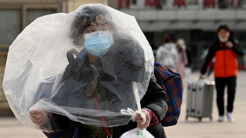 Fotografija: Ženska, ki uporablja plastično vrečko za dodatno zaščito, se sprehaja pred pekinško železniško postajo v Pekingu. Na Kitajskem je vse v znamenju največjega praznika v letu, lunarnega novega leta, ki bo letos v znamenju tigra. Foto: Noel Celis/Afp