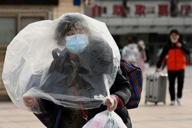 Ženska, ki uporablja plastično vrečko za dodatno zaščito, se sprehaja pred pekinško železniško postajo v Pekingu. Na Kitajskem je vse v znamenju največjega praznika v letu, lunarnega novega leta, ki bo letos v znamenju tigra. Foto: Noel Celis/Afp