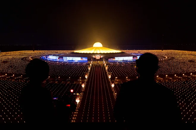 Pogled na tempelj Wat Dhammakaya, obdan s prižganimi svečami med praznovanjem Makha Buche, severno od Bangkoka. Budistično praznovanje in državni praznik Makha Bucha, ki ga Tajci praznujejo na polno luno tretjega lunarnega meseca (običajno v februarju oziroma marcu), spominja na pridiganje Bude 1250 razsvetljenim menihom. Praznuje se na templjih po Kambodži, Laosu, Mjanmaru in na Tajskem. Foto: Jack Taylor/Afp
