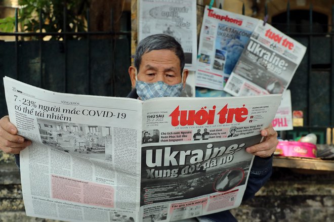 Moški prebira vietnamski časopis z naslovnico o ruskem napadu na Ukrajinu. FOTO: Nam Nguyen/AFP
