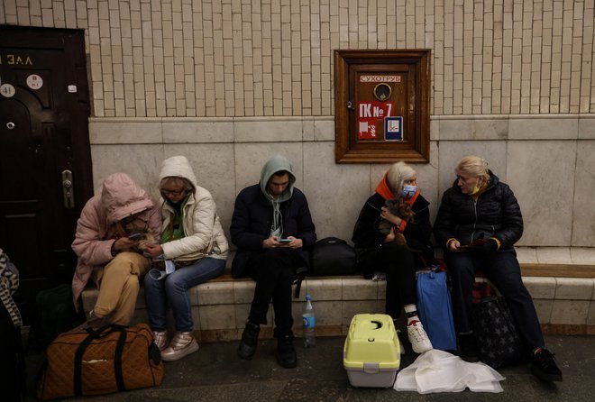 Ljudje zbrani na postaji podzemne železnice, ko iščejo zavetje pred pričakovanimi ruskimi zračnimi napadi v Kijevu. FOTO: Umit Bektas/Reuters
