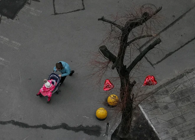 Ženska z otrokom hiti v bombno zaklonišče med zračnim alarmom v Kijevu. FOTO: Gleb Garanich/Reuters
