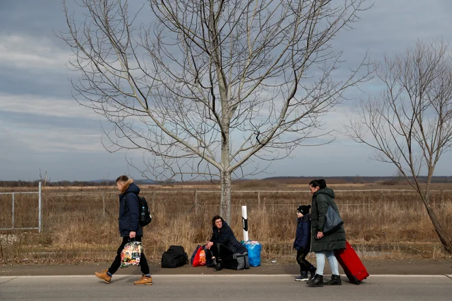 Ljudje iz Ukrajine bežijo proti Madžarski, potem ko je Rusija začela z vojaško invazijo. FOTO: Bernadett Szabo/Reuters

