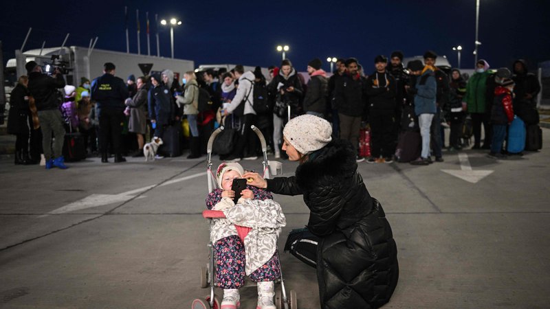 Fotografija: Ukrajinka govori z otrokom na meji z Romunijo. FOTO: Daniel Mihailescu/AFP
