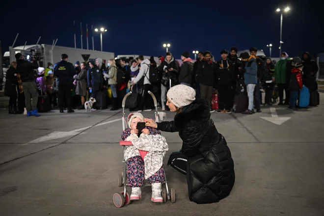 Ukrajinka govori z otrokom na meji z Romunijo. FOTO: Daniel Mihailescu/AFP