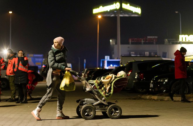 Ukrajinka, ki z otrokom čaka na prevoz na Poljsko. FOTO: Jakub Stezycki/Reuters
