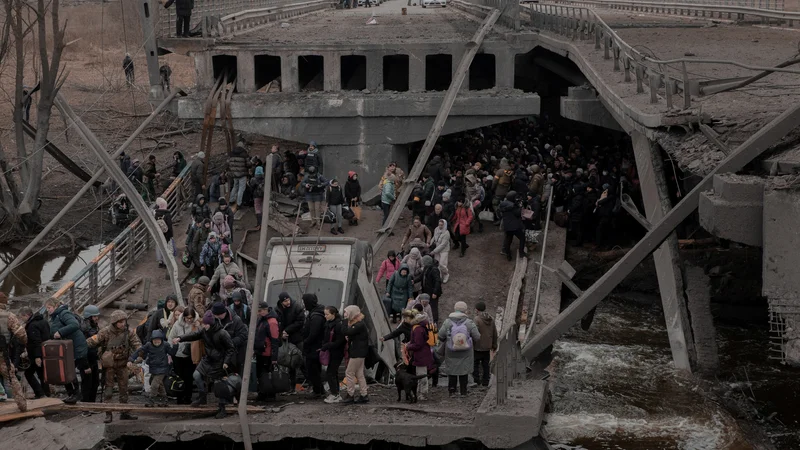 Fotografija: Ljudje, ki skušajo zapustiti mesto Irpin v bližini Kijeva, ob prečkanju ruševin mostu. FOTO: Agencja Wyborcza.pl via Reuters