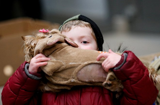 Otrok s svojim kužkom na postaji v mestu Zahony na Madžarskem. FOTO: Bernadett Szabo/Reuters
