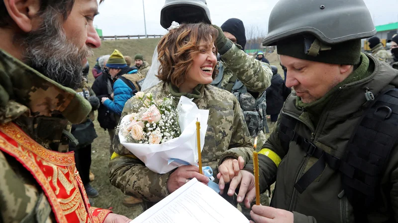 Fotografija: Pripadnika ukrajinskih teritorialnih obrambnih sil Lesja Ivaščenko in Valerij Fylymonov sta se poročila sredi ruske invazije kar na kontrolni točki v Kijevu. Foto: Mykola Tymchenko/Reuters