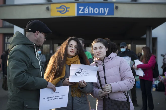 Člani in članice Ukrajinskega mladinskega simfoničnega orkestra na železniški postaji Záhony ob ukrajinski meji. Z dvema avtobusoma so jih prepeljali v Ljubljano. FOTO: Jure Eržen/Delo
