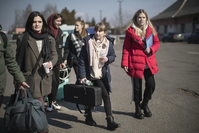 Člani in članice Ukrajinskega mladinskega simfoničnega orkestra na železniški postaji Záhony ob ukrajinski meji. Z dvema avtobusoma so jih prepeljali v Ljubljano. FOTO: Jure Eržen/Delo
