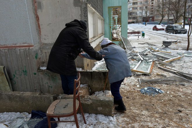 Moški pomaga ranjeni gospe v Harkovu. FOTO: Sergey Bobok/AFP
