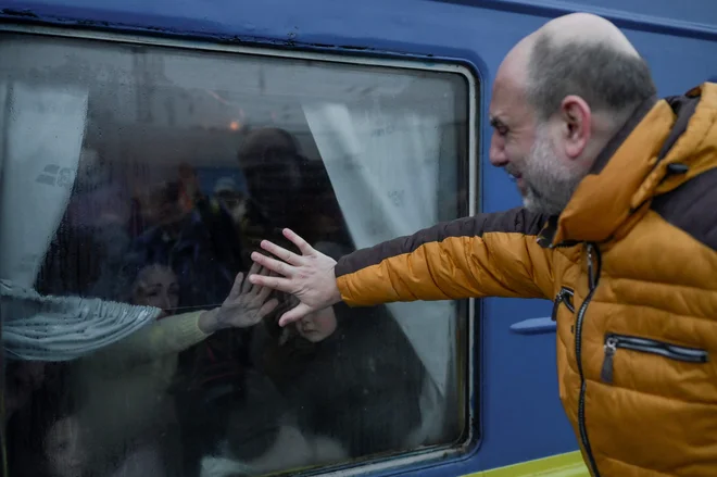 Oče joče med poslavljanjem od svoje družine pred evakuacijskim vlakom na osrednji železniški postaji v Odesi. Odesa, za katero se Ukrajina boji, da bi lahko bila naslednja tarča ruske ofenzive na jugu države, je glavno pristanišče države in je ključno za njeno gospodarstvo. FOTO: Bulent Kilic/AFP