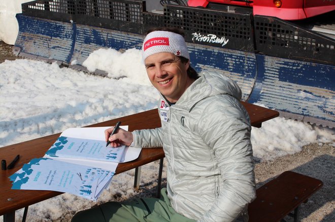 Olimpijec Žan Košir podpisuje diplome za udeležence Zimskega dneva. Foto Arhiv Podjetja Si Splet
