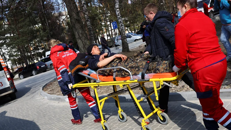 Fotografija: Po raketnem napadu na vojaško bazo Javoriv blizu poljske meje reševalci oskrbujejo ranjence. FOTO: Kai Pfaffenbach/Reuters