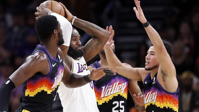 Fotografija: LeBron James išče podajo med Devinom Bookerjem (desno) in Deandrejem Aytonom (levo). FOTO: Chris Coduto/AFP