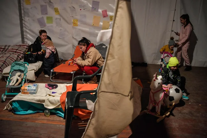 Ženske z otroki v šotoru za humanitarno pomoč na mejnem prehodu Medyka na jugovzhodu Poljske. FOTO: Louisa Gouliamaki/AFP
