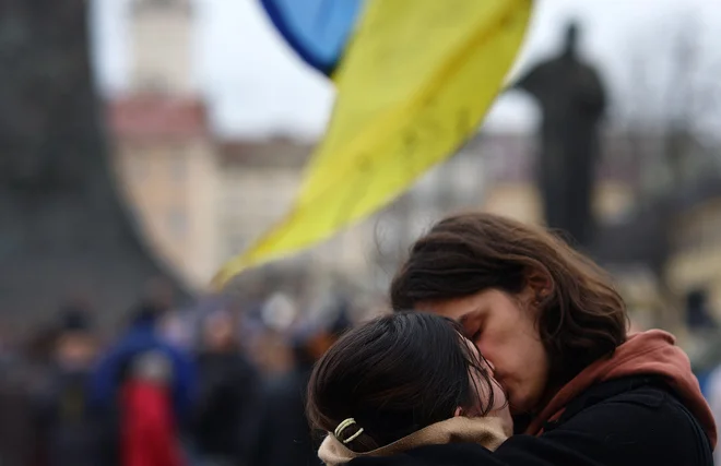 Par se poljubija med poslušanjem uličnega koncerta simfoničnega orkestra Za svobodno nebo in proti ruski invaziji na Ukrajino, v središču Lvova. Foto: Kai Pfaffenbach/Reuters
