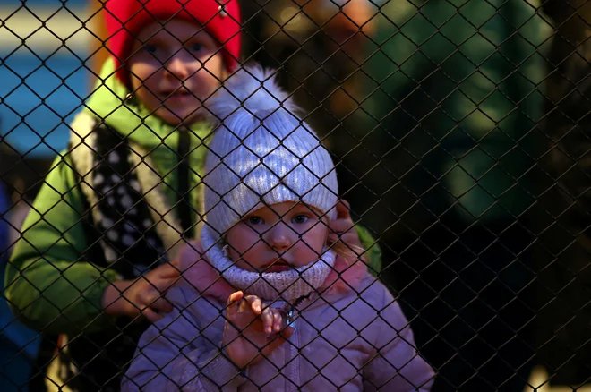 Ukrajinska begunka Karolina, stara tri leta iz Nikopola, gleda skozi ograjo na peronu, ko je prispela na železniško postajo Przemysl Glowny na Poljskem. FOTO: Hannah Mckay/Reuters
