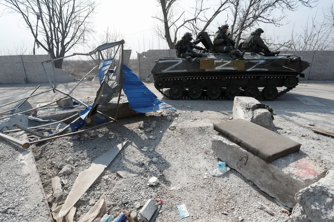 Uslužbenci proruskih čet na vrhu oklepnega vozila v pristaniškem mestu Mariupol. FOTO: Alexander Ermochenko/Reuters
