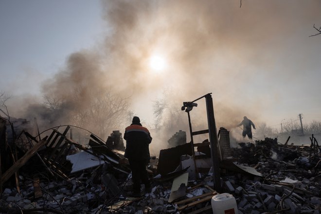 Prebivalci gasijo požar, potem ko je bombni napad uničil družinsko hišo v severnem okrožju Harkova. FOTO: Thomas Peter/Reuters
