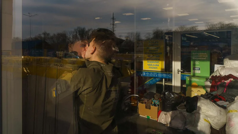 Fotografija: Par Lina in Vlad, oba prostovoljca, se poljubita v prijavnem centru v Zaporožju. Humanitarni konvoj končno zapušča opustošeno južno pristanišče Mariupol, vključno z reševalnimi vozili z ranjenimi otroki. Foto: Emre Caylak/Afp