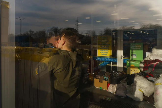 Par Lina in Vlad, oba prostovoljca, se poljubita v prijavnem centru v Zaporožju. Humanitarni konvoj končno zapušča opustošeno južno pristanišče Mariupol, vključno z reševalnimi vozili z ranjenimi otroki. Foto: Emre Caylak/Afp