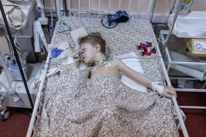 Triletni deček Dima, ki je bil ranjen med obstreljevanjem Mariupola, se trenutno zdravi v postelji na otroškem oddelku bolnišnice v Zaporožju. Foto: Marko Djurica/Reuters
