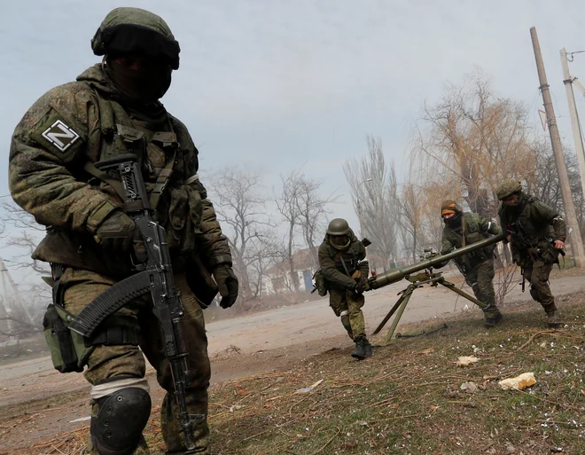 Pripadniki proruskih čet nosijo protitankovski izstrelek granat v Mariupolju. FOTO: Alexander Ermochenko/Reuters
